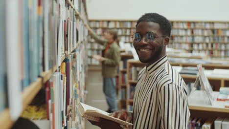 Porträt-Eines-Glücklichen-Afro-Mannes-Neben-Bücherregalen-In-Der-Bibliothek